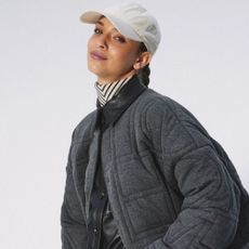 Woman wearing white cap and grey quilted jacket from The Outnet.