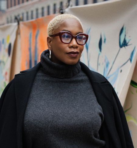 Kelly Augustine in a gray sweater dress, black coat, and zebra pouch.