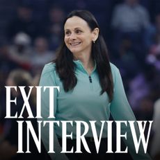 Sandy Brondello, smiling courtside in a teal zip-up top, during a WNBA game. The words &ldquo;Exit Interview&rdquo; appear in bold white text across the lower part of the image.